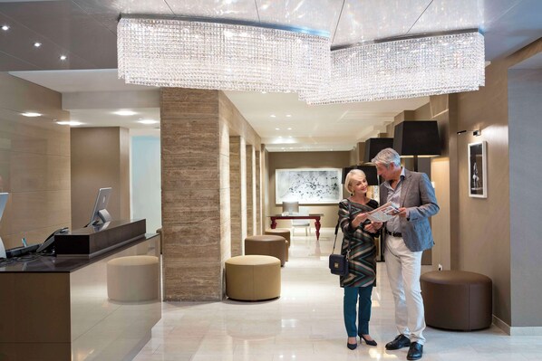 A modern hotel lobby with a reception desk, seating areas, and a large chandelier. - The Harmonie Vienna, BW Premier Collection (Vienna)