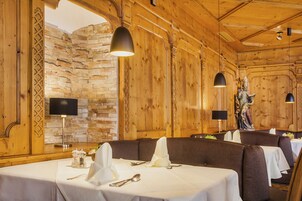 A restaurant with wooden walls, stone accents, and tables set for dining.