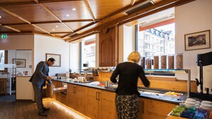Una cocina moderna con armarios de madera, una encimera con diversos alimentos y un ventanal con vistas a edificios.