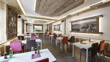 A restaurant with wooden beams, stone walls, and a large painting of a cyclist. Tables are set with menus and condiments.