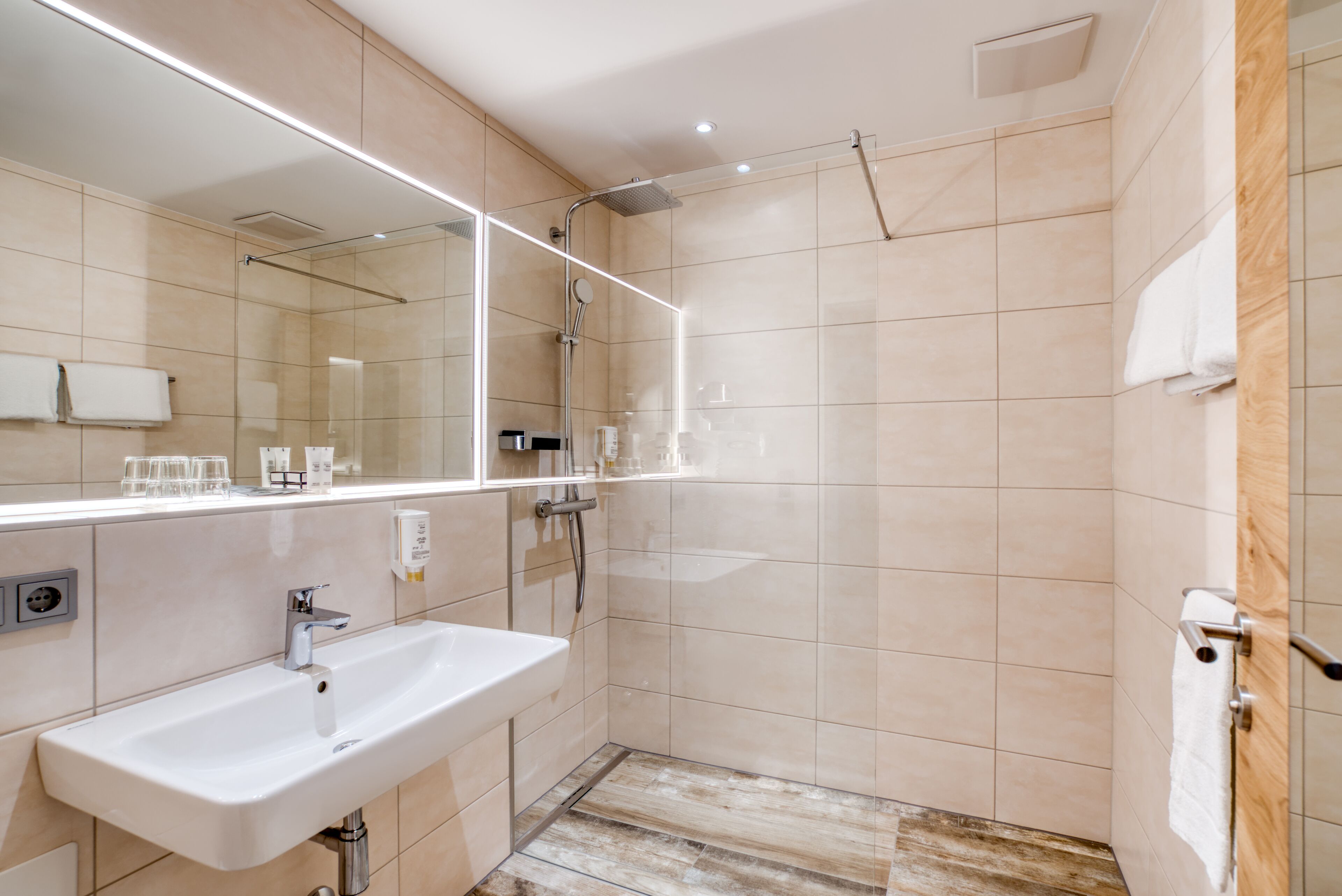 A modern bathroom with a large mirror, a sink, and a shower area.