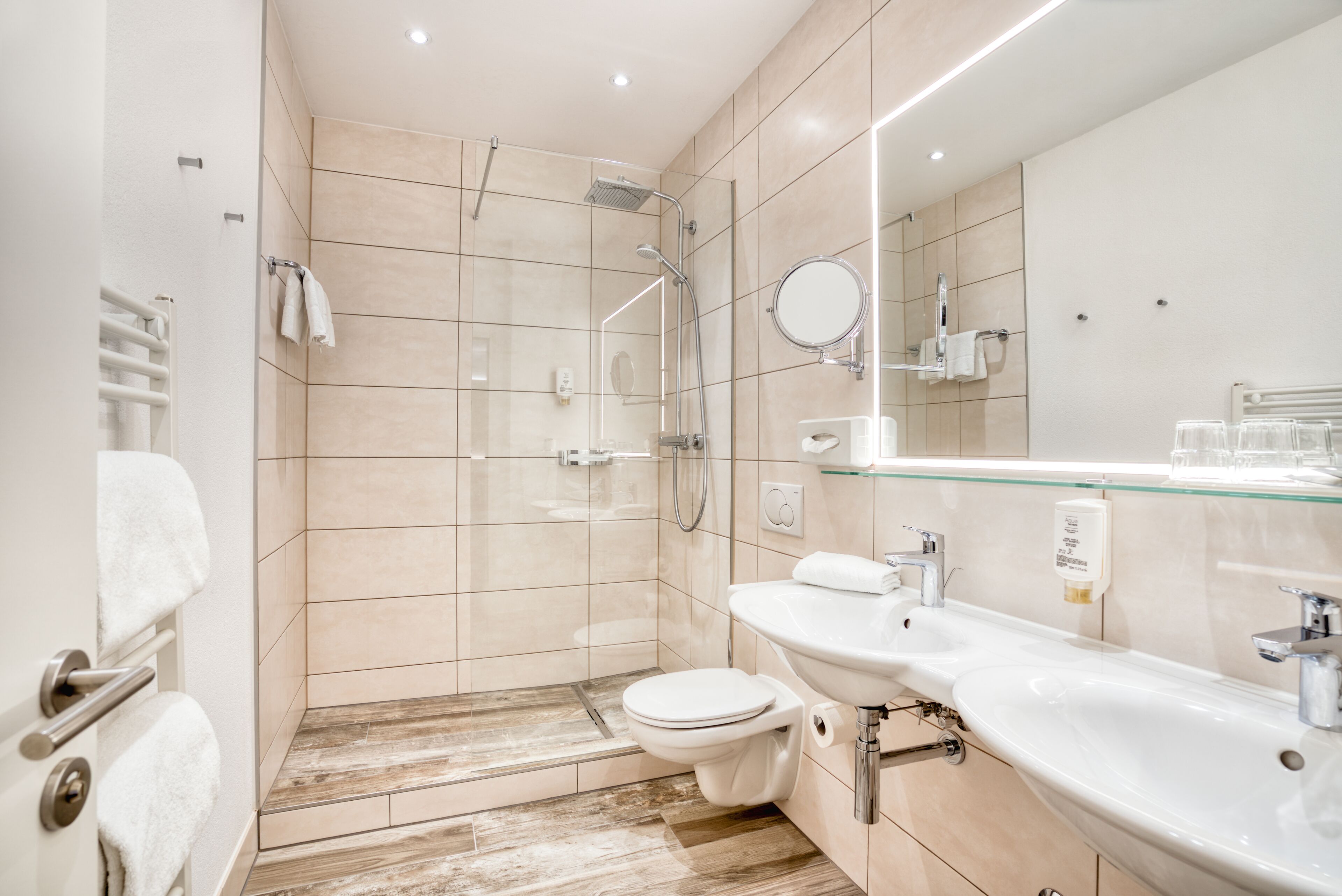 Un baño moderno con cabina de ducha de vidrio, un lavabo blanco y un inodoro.