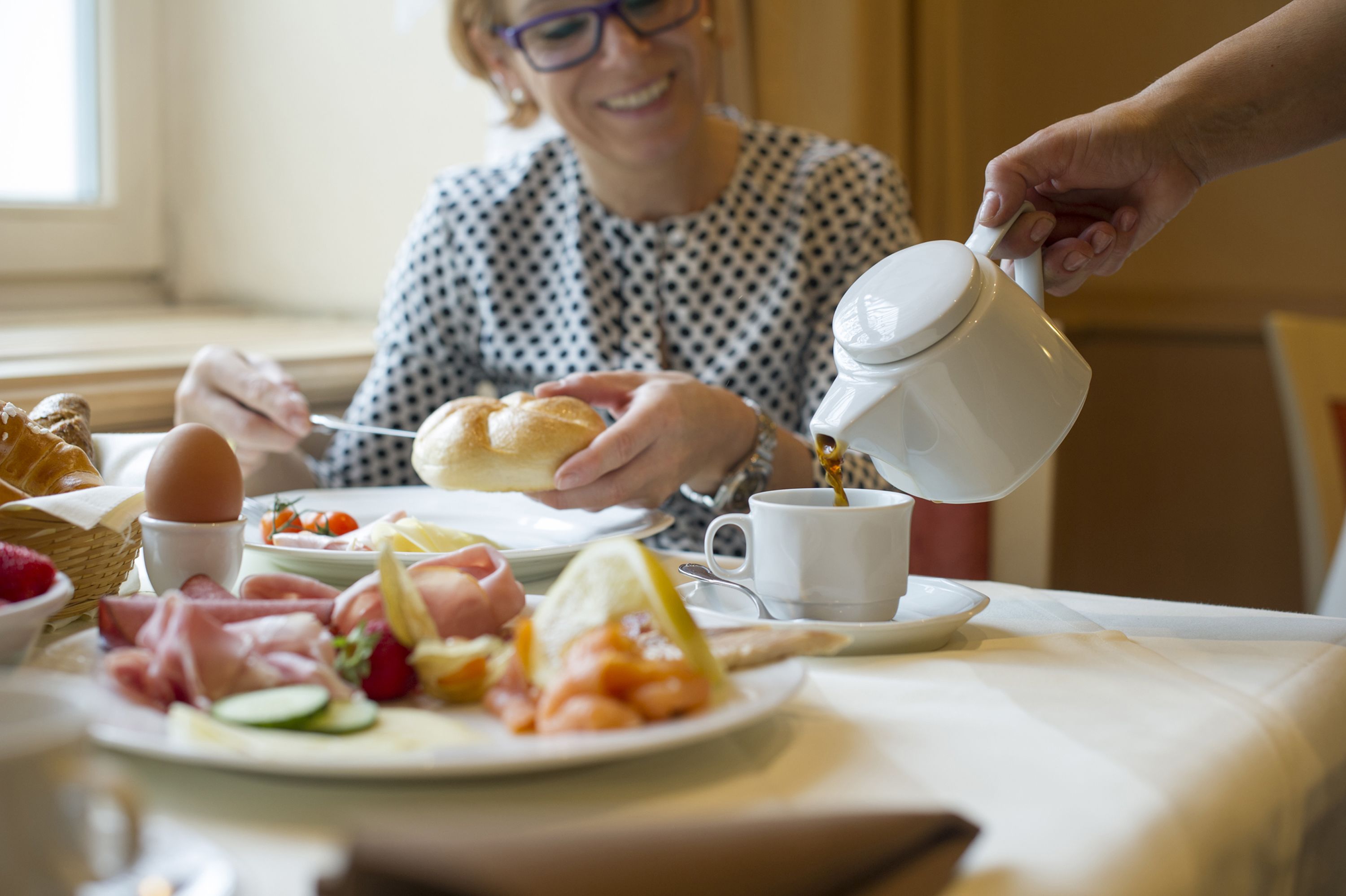 A breakfast setting with a variety of food items on a table, including bread, eggs, and fruits.
