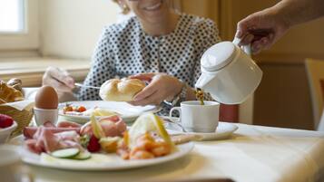 A breakfast setting with a variety of food items on a table, including bread, eggs, and fruits.
