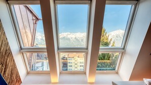 Habitación con tragaluces que ofrece vistas a montañas y edificios.