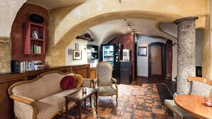 A cozy interior with a wooden bench, a patterned sofa, and a stone column. - Hotel Mondschein (Innsbruck)
