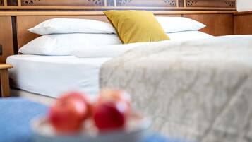 Una cama con almohadas blancas y amarillas, un cabecero de madera y una colcha azul.