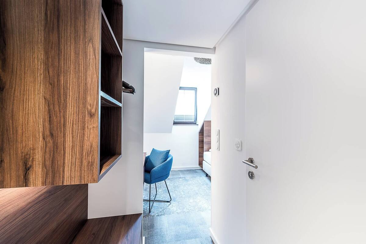 A modern interior with a wooden floor, a blue chair, and a white door leading to another room.