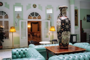 A lobby with a large decorative vase on a table, green upholstered seating, and a chandelier. - Pannonia Hotel (Sopron)
