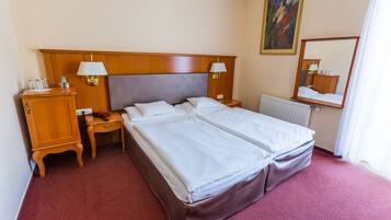 Habitación de hotel con cama doble, dos mesitas de noche, armario de madera, radiador y un cuadro en la pared.