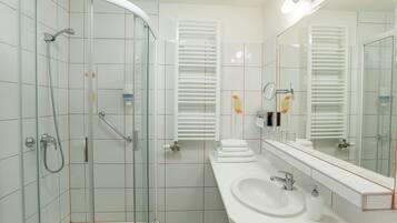 Une salle de bain moderne avec une douche à parois de verre, un lavabo blanc et un grand miroir.