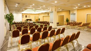 A conference room with rows of red chairs and a stage at the front. - Pannonia Hotel (Sopron)
