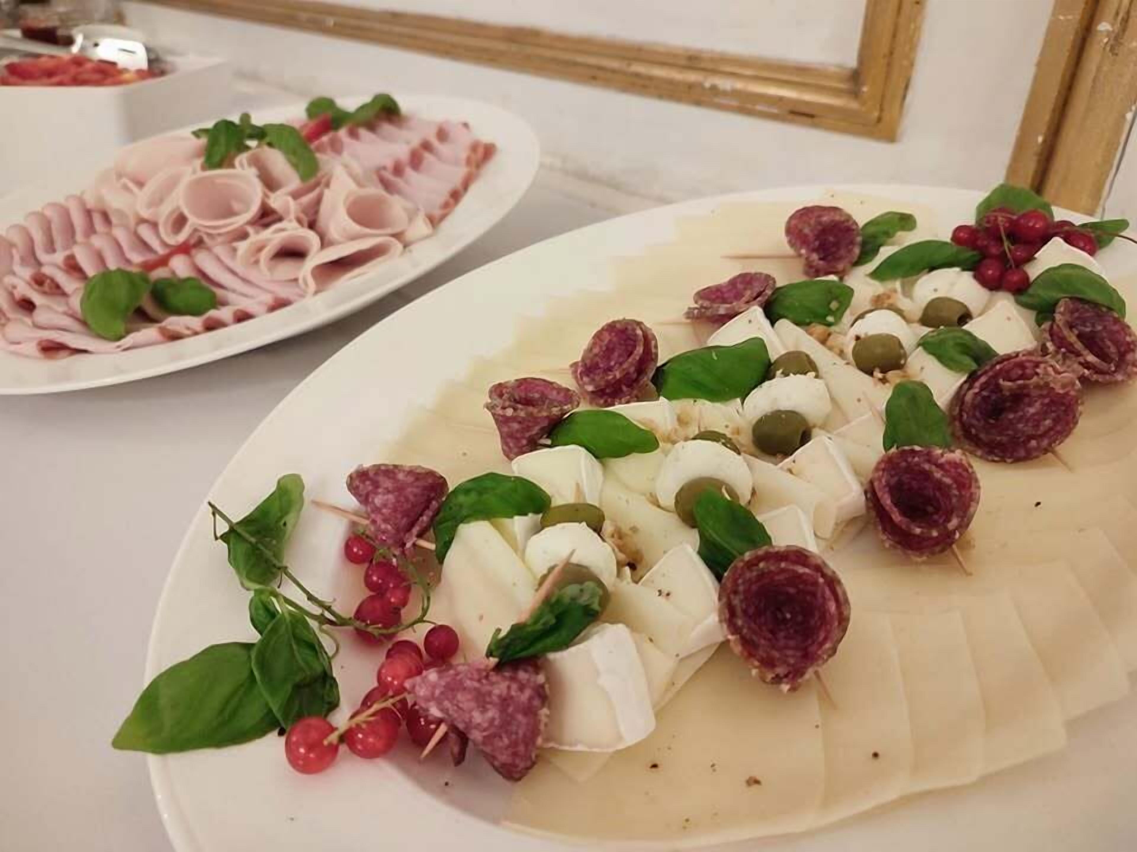Un plato de embutidos y quesos adornado con hojas verdes y uvas.