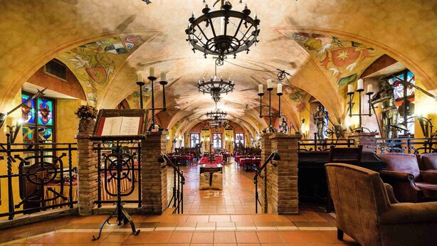 An interior with arched ceilings, chandeliers, and stained glass windows. - Pytloun Old Armoury Hotel Prague (Prague)
