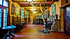 A cozy bar with wooden furniture, a large tree sculpture, and a tiled floor. - Pytloun Old Armoury Hotel Prague (Prague)