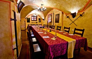 A long dining table with red tablecloths and chairs, set in a room with arched ceilings and wooden walls.