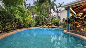 A clear blue pool surrounded by tropical plants and a stone wall. - Trinity Beach Pacific (Trinity Beach)