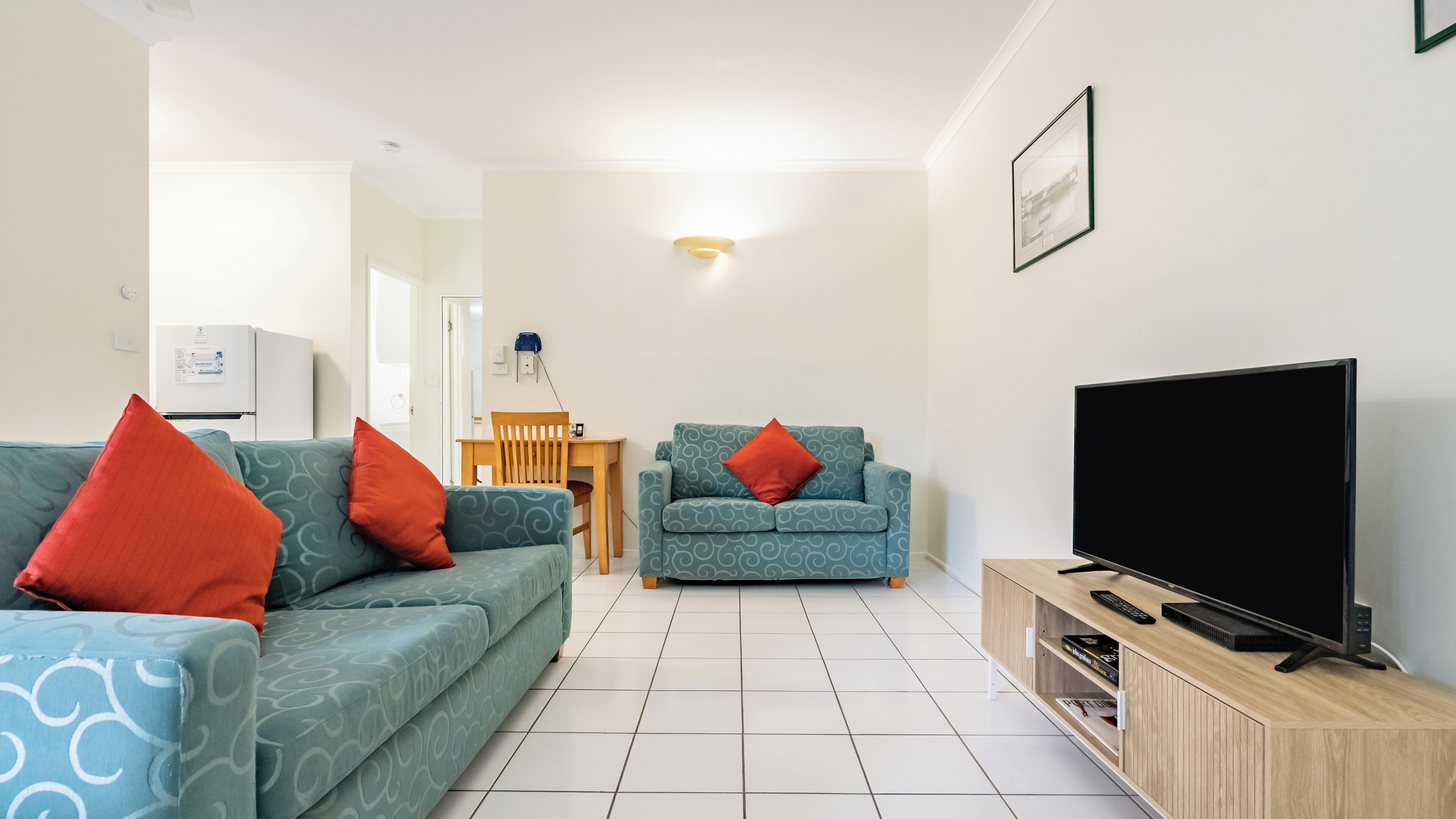 A living room with two sofas, a TV, and a wooden TV stand.