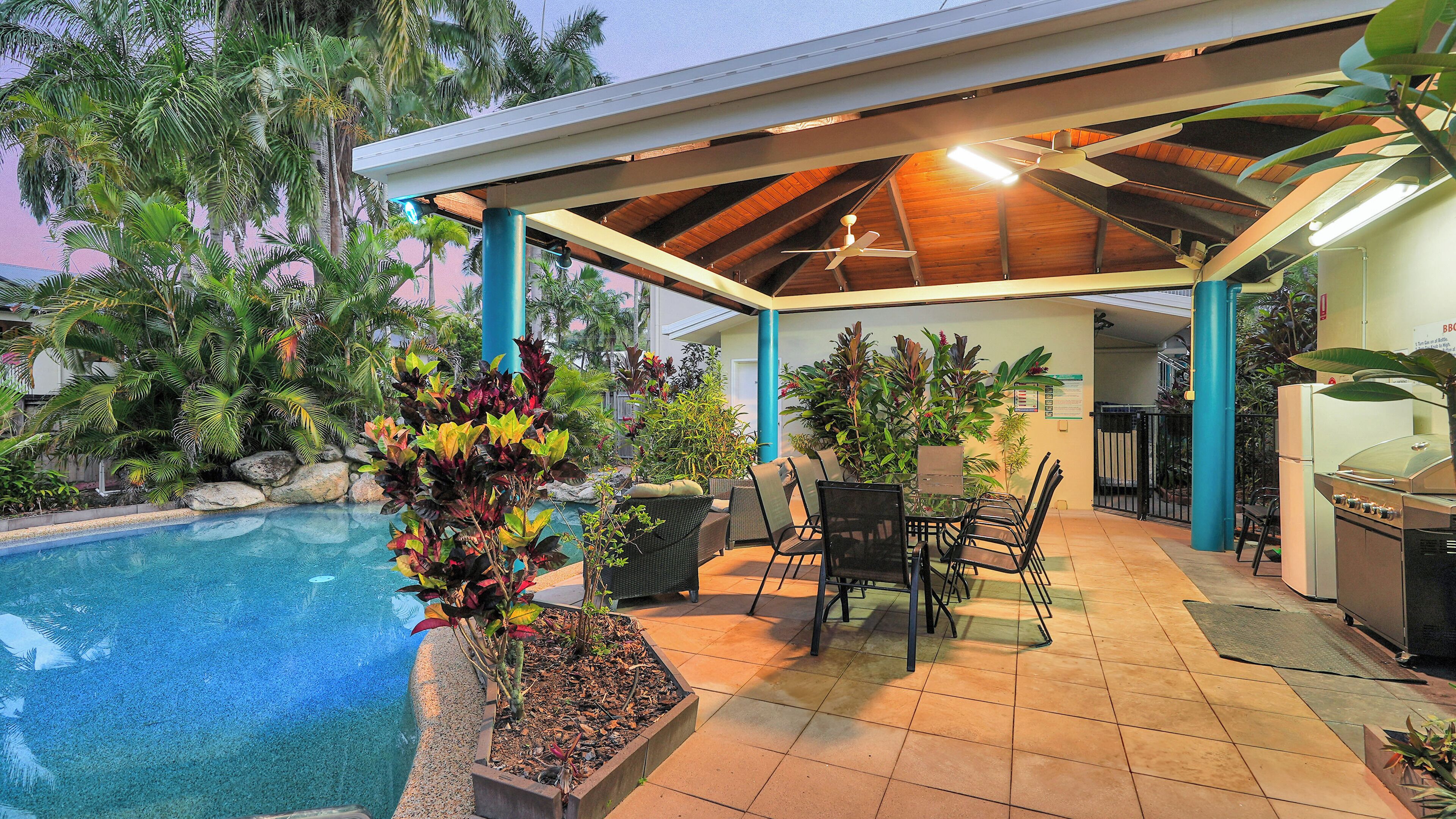 A covered outdoor area with a pool, seating, and a barbecue grill.