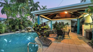 A poolside area with a covered seating area, a BBQ station, and a pool. - Trinity Beach Pacific (Trinity Beach)