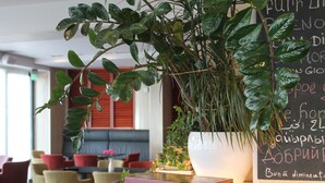 Un décor intérieur moderne avec une grande plante en pot, un tableau noir avec du texte et un petit livre posé sur une table en bois.