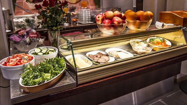 Un buffet proposant une variété de plats, notamment des fruits, des légumes et des salades.