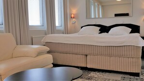 Une chambre à coucher bien aménagée, avec un grand lit, un canapé, une table de chevet et une commode.