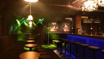 A bar area with multiple stools, a bar counter, and a chandelier.