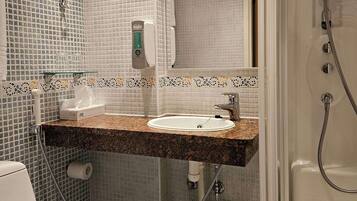 Un baño con lavamanos, inodoro y ducha.