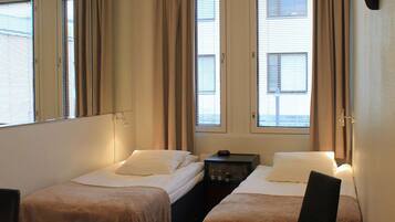 A hotel room with two single beds, a desk, a chair, and a large mirror.