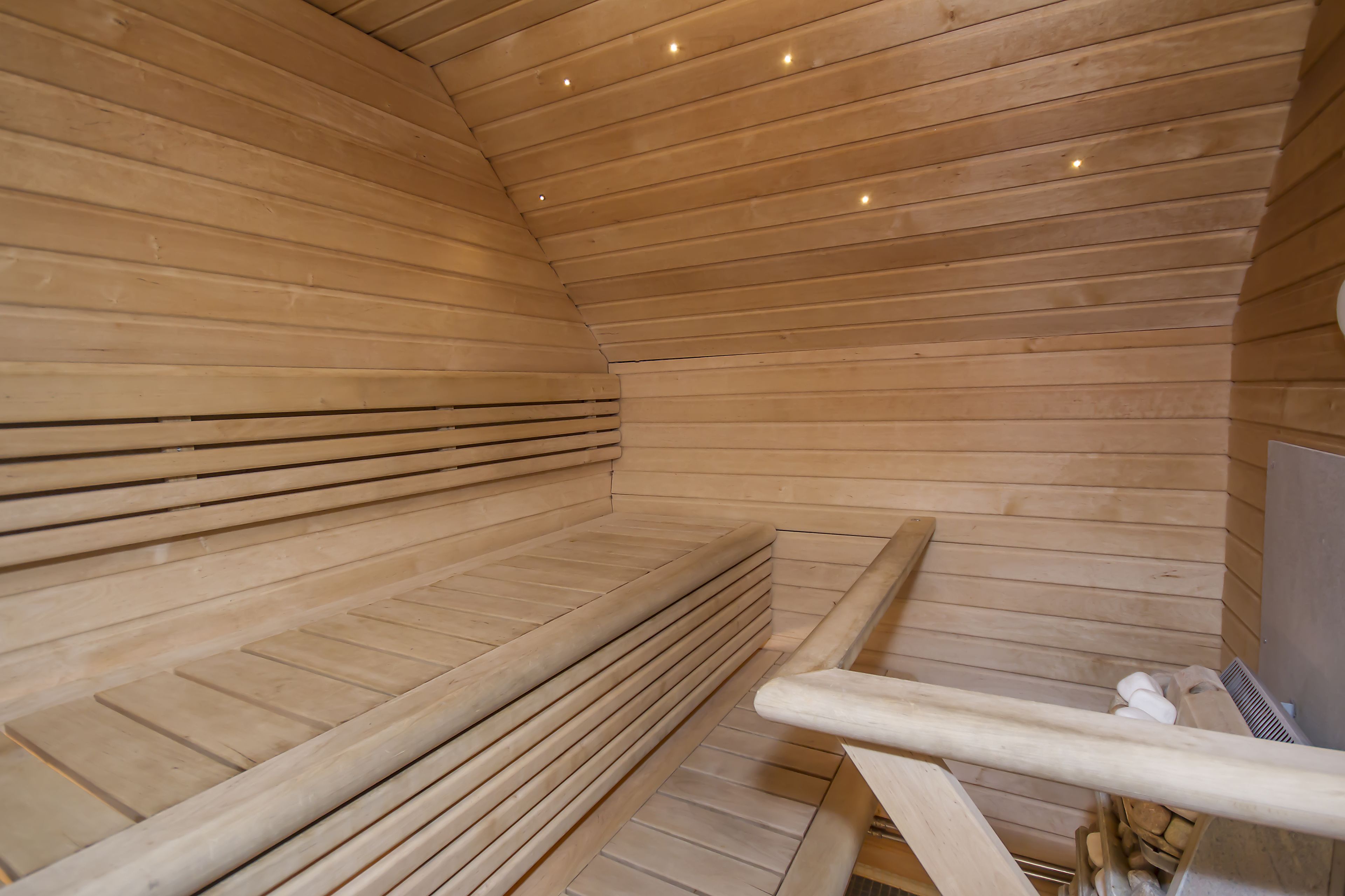 A sauna with wooden benches and a metal railing.