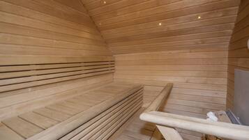 A sauna with wooden benches and a metal railing.