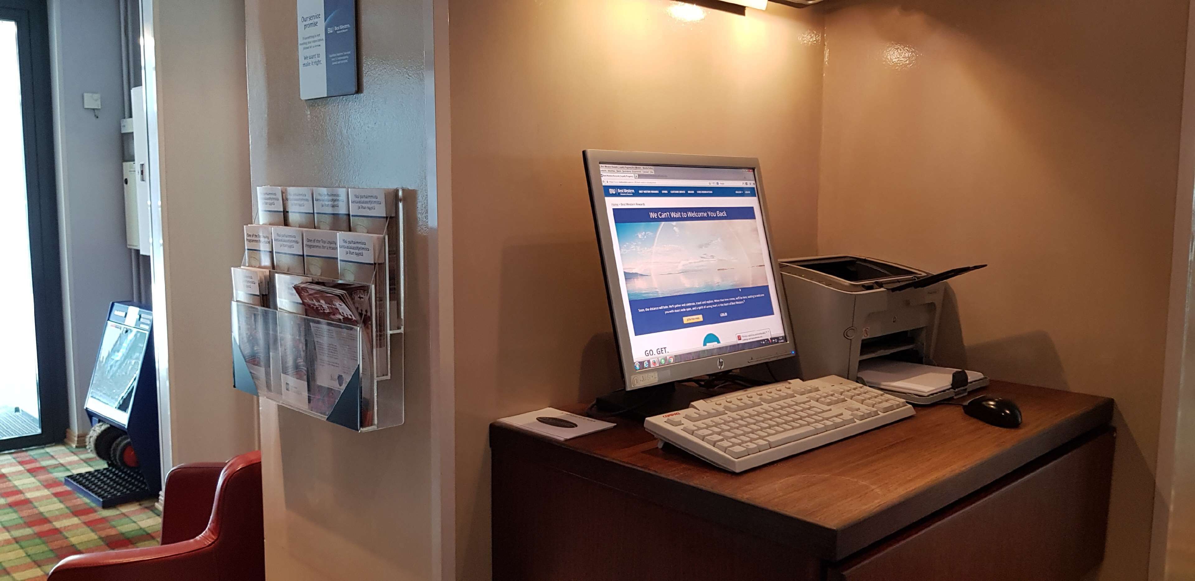 A reception desk with a computer monitor displaying a website, a keyboard, a mouse, and a trash bin.