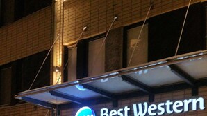 L’extérieur de l’hôtel Best Western Apollo se distingue par son enseigne lumineuse bien visible, ses grands pots de plantes et son entrée abritée.
