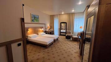 A hotel room with two beds, a desk, a chair, a mirror, and a carpeted floor.