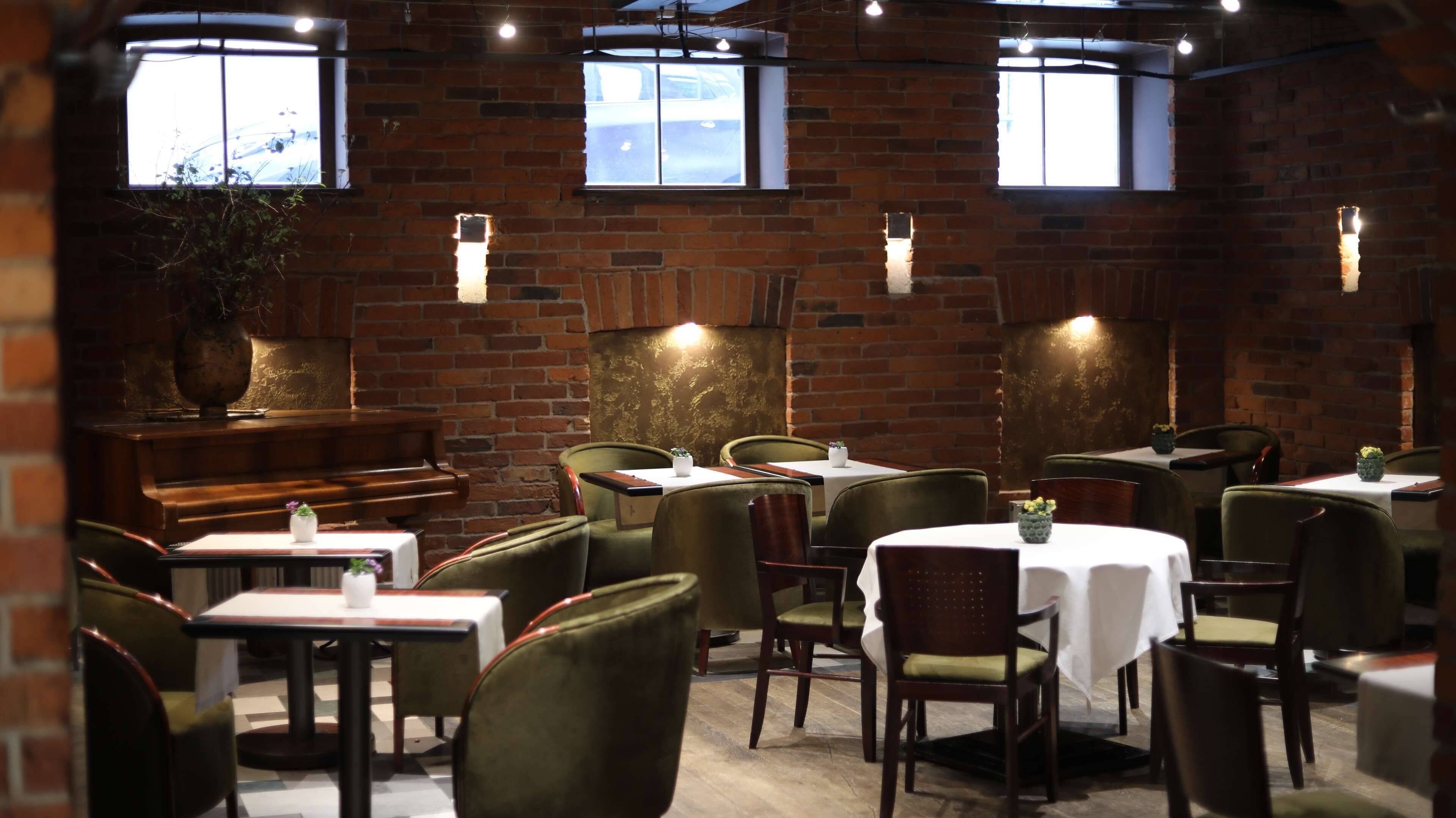A restaurant with brick walls, multiple tables and chairs, and a piano.