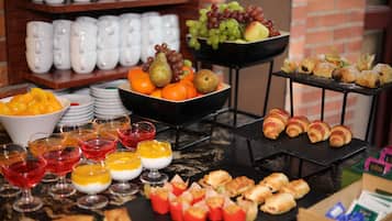 Un buffet con diverse pietanze, tra cui frutta, pasticcini e dolci.