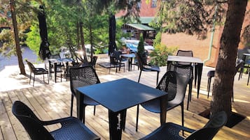 An outdoor patio with wooden flooring, black metal chairs, and tables.