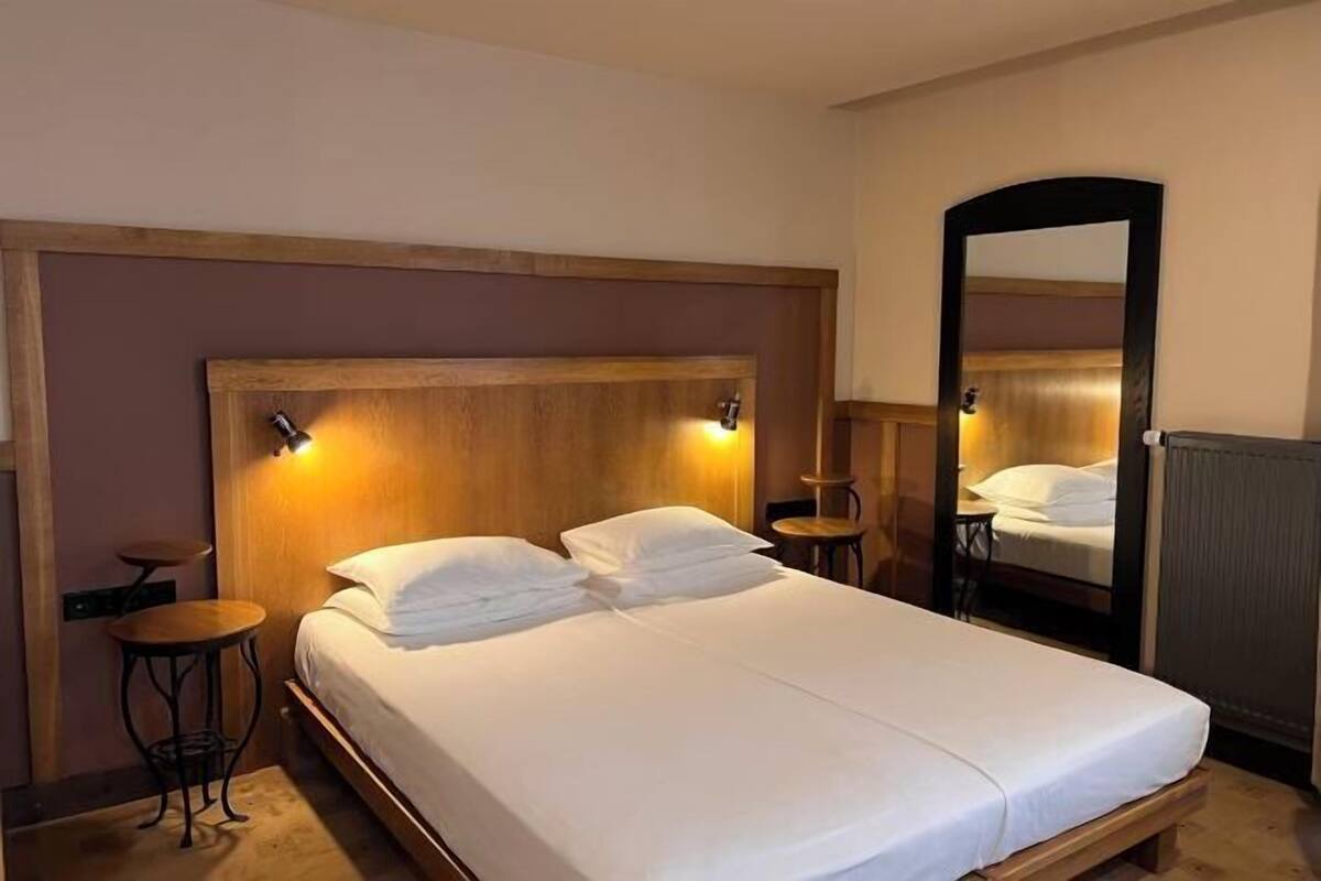 A single bed with a wooden headboard, two bedside tables, a mirror, and a radiator.