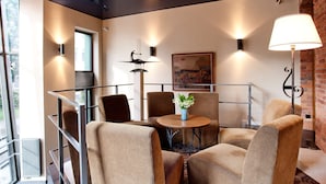 A modern interior with a glass table surrounded by cushioned chairs, a floor lamp, and wall-mounted lights. - Best Western Santakos Hotel (Kaunas)
