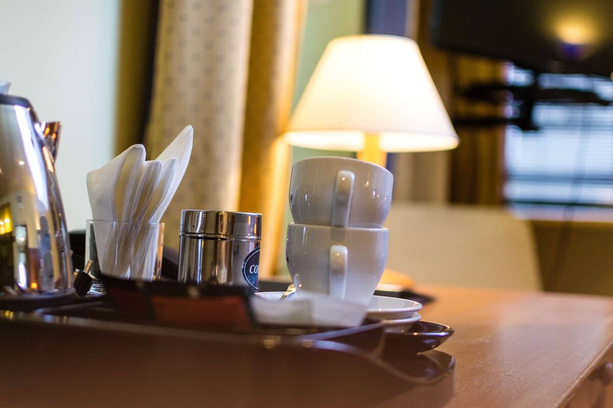 A table setting with a coffee maker, cups, and a napkin holder.