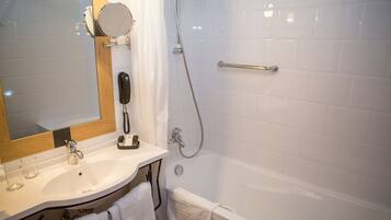 A bathroom with a sink, mirror, and shower.