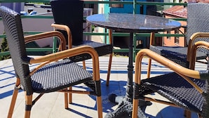 A terrace with wicker chairs and a table, overlooking a building with a green roof and multiple windows. - Best Western Santakos Hotel (Kaunas)