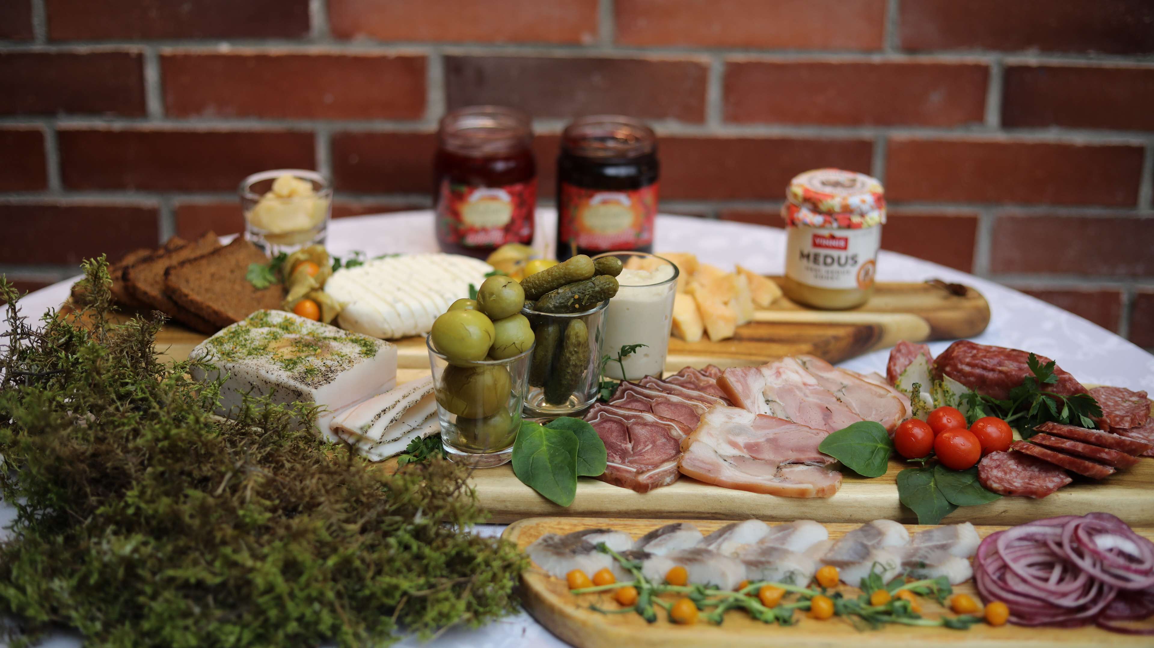 A variety of cheeses, cured meats, olives, and pickles on a wooden board.