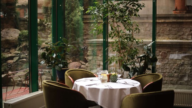 A table set for two with a view of a stone wall and greenery outside. - Best Western Santakos Hotel (Kaunas)