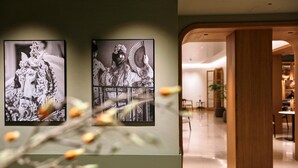 Two black and white photographs on a wall, a wooden column, and a glimpse of a dining area. - Becquer Hotel, Historic City Center (Seville)