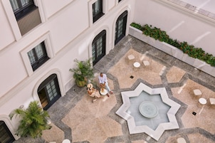 An aerial view of a courtyard with a fountain, seating areas, and potted plants.