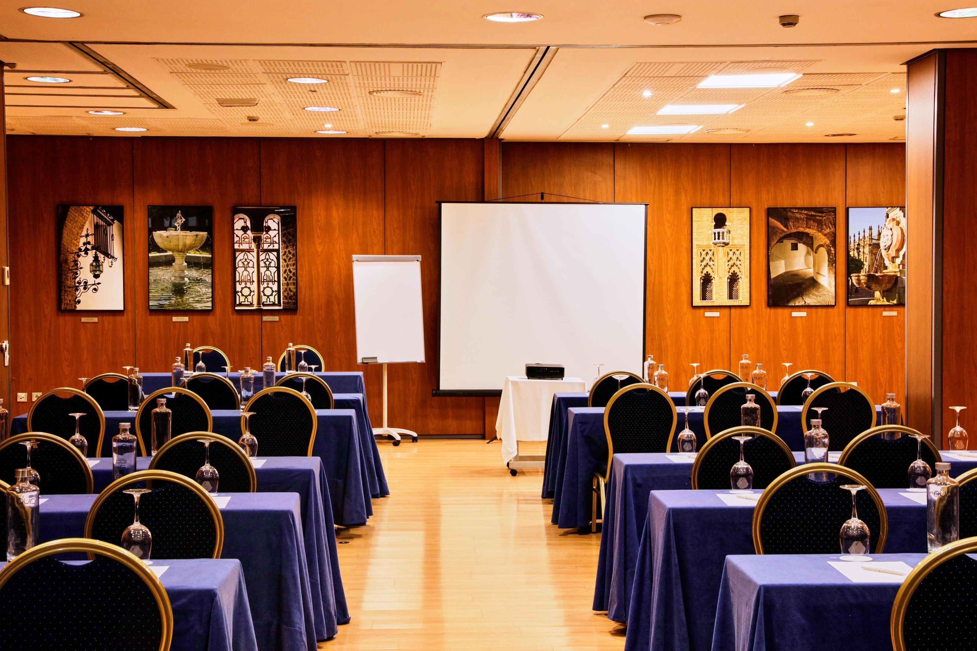 A conference room with rows of tables, chairs, and a projection screen.
