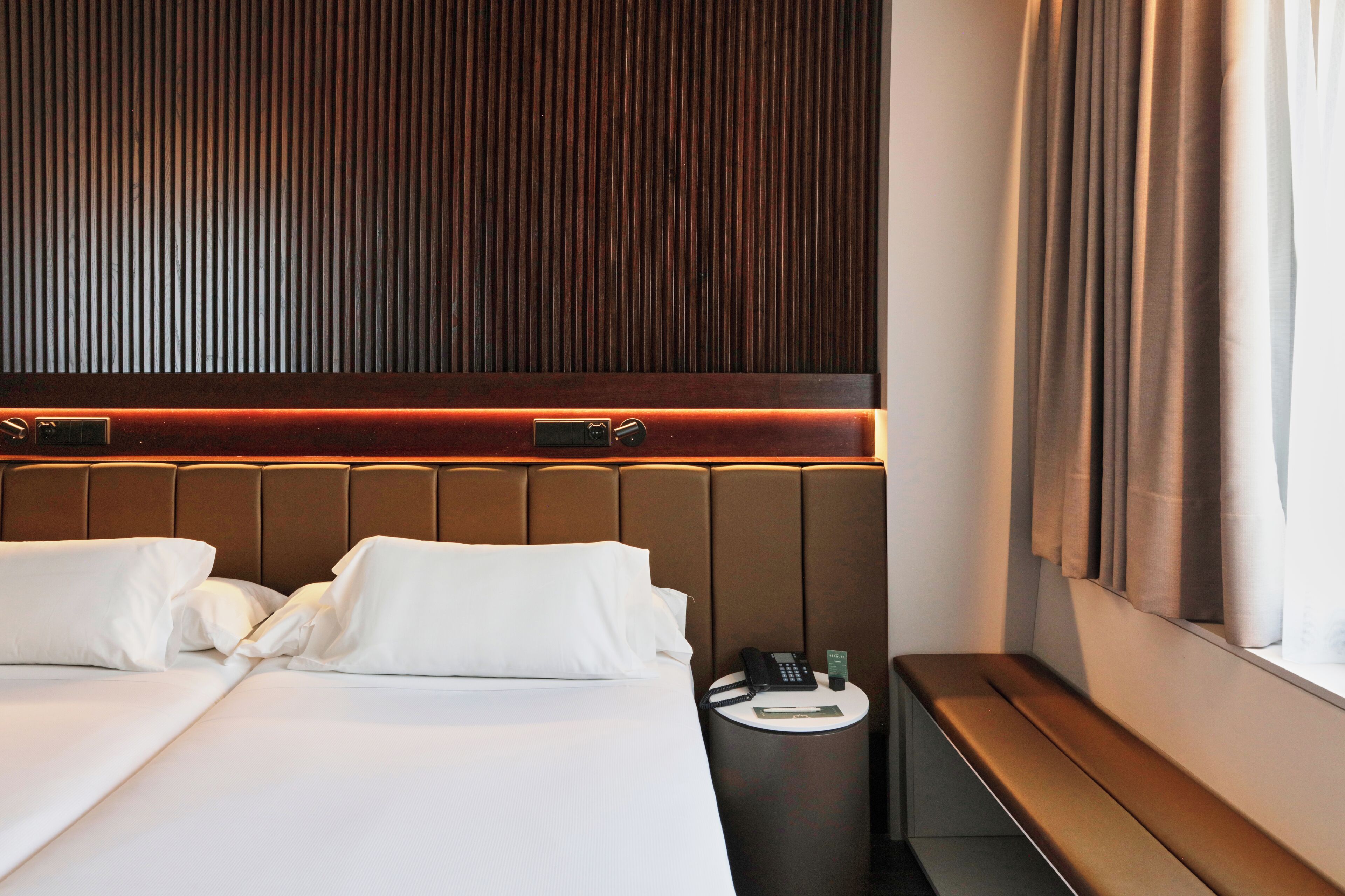 Una habitación de hotel con una cama grande, una mesita de noche y una ventana con cortinas.