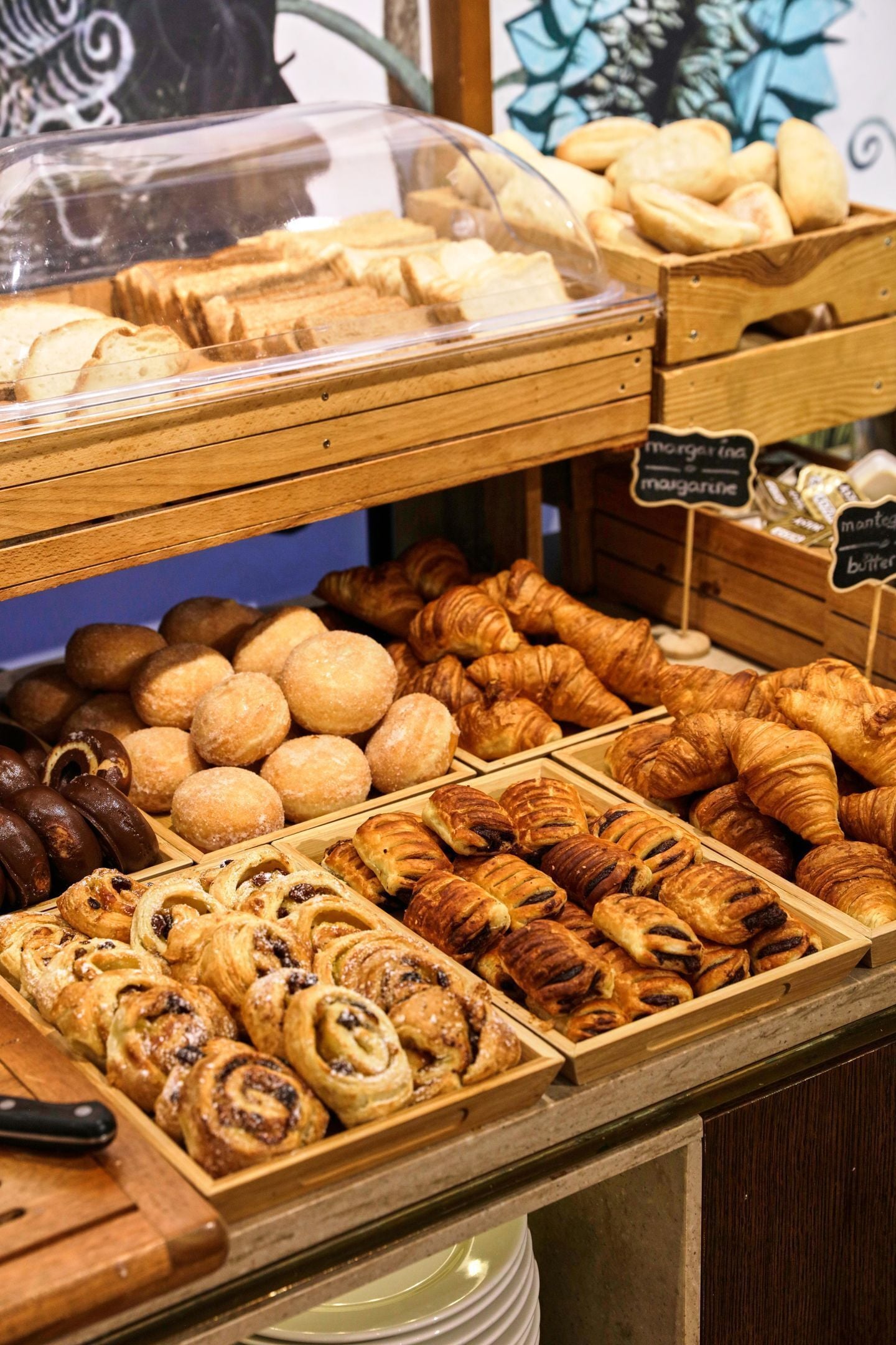 Mostrador de panadería con diversos pasteles y pan, incluyendo cruasanes y rollos de canela.